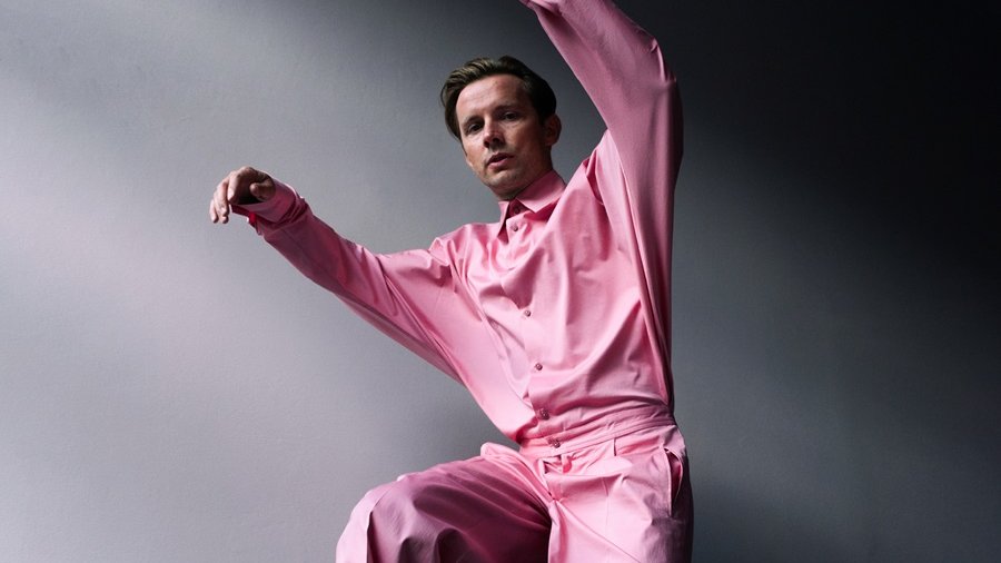 Zdjęcie artysty w różowej koszuli i spodniach.