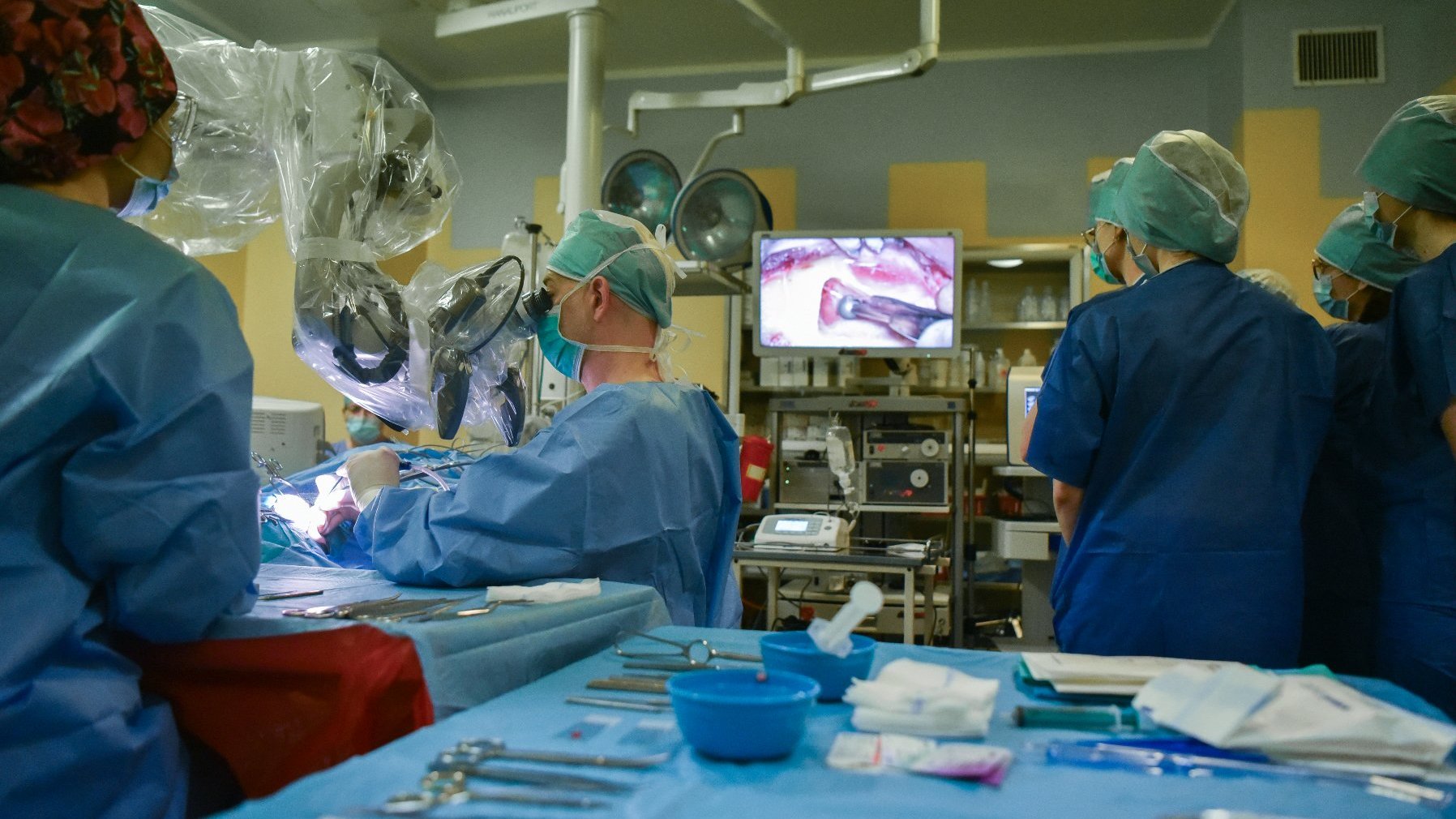 Na zdjęciu lekarze podczas operacji, widać studentów patrzących w monitor