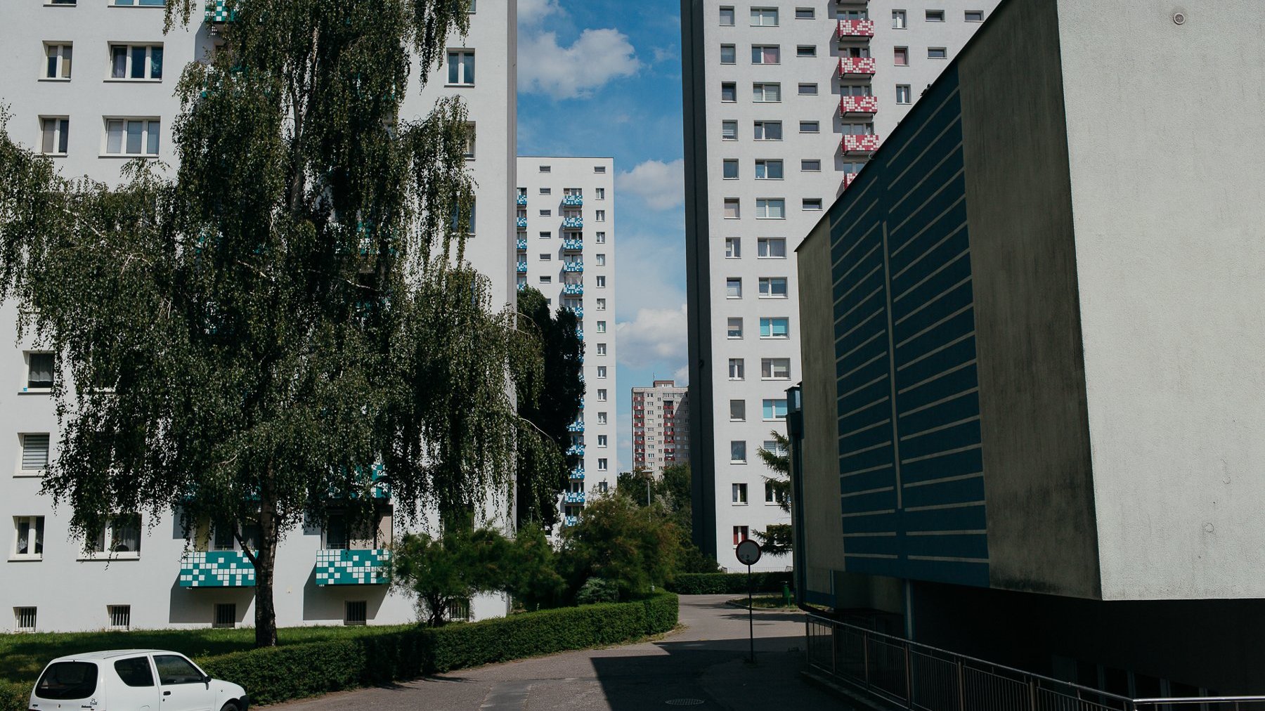 Zdjęcie przedstawia widok na bloki i osiedlową ulicę.