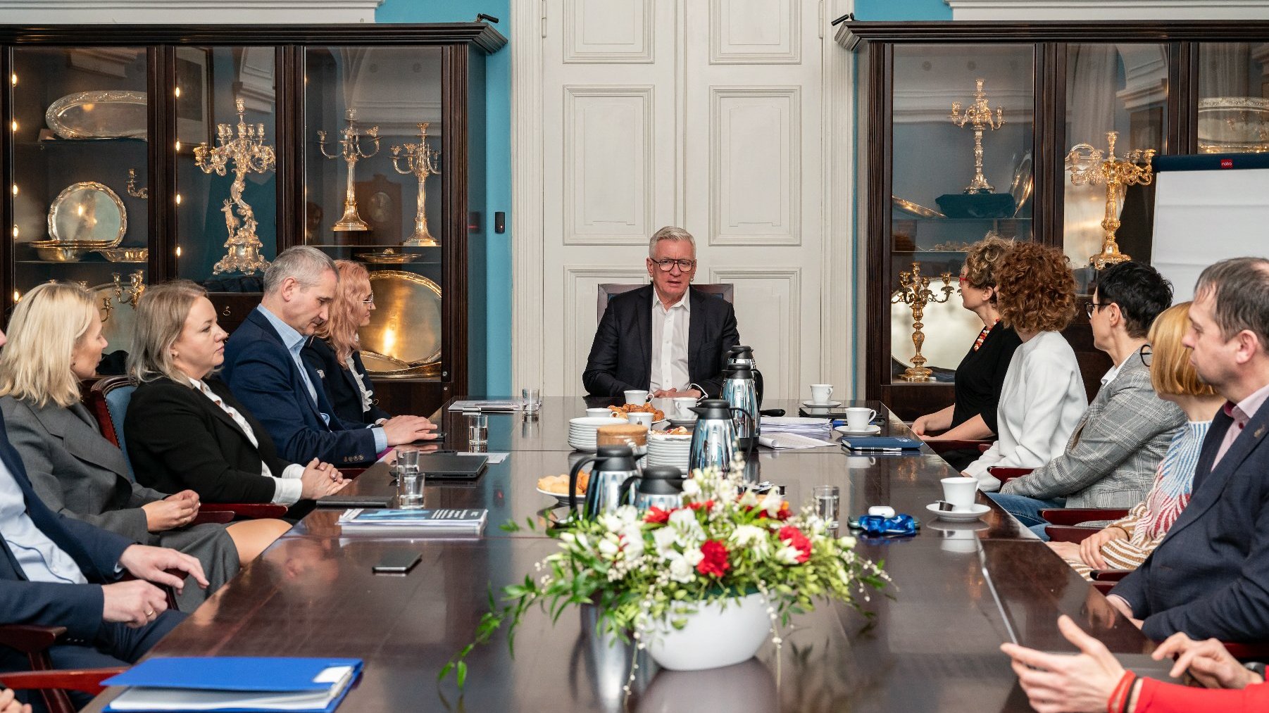 Na zdjeciu grupa ludzi za stołem, u szczytu stołu siedzi prezydent Poznania