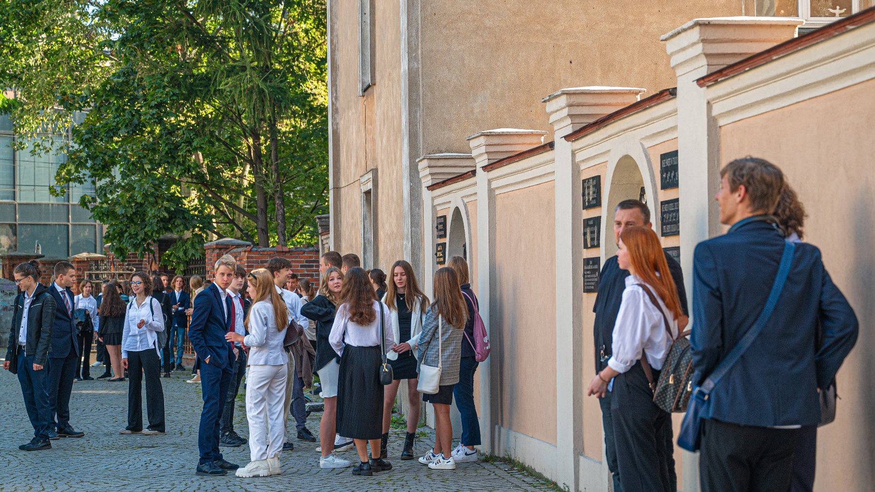 Zdjęcie przedstawia uczniów stojących przed szkołą.