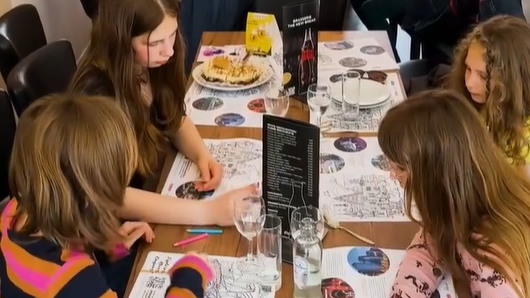 Na zdjęciu dzieci przy stoliku, kolorują kolorowanki