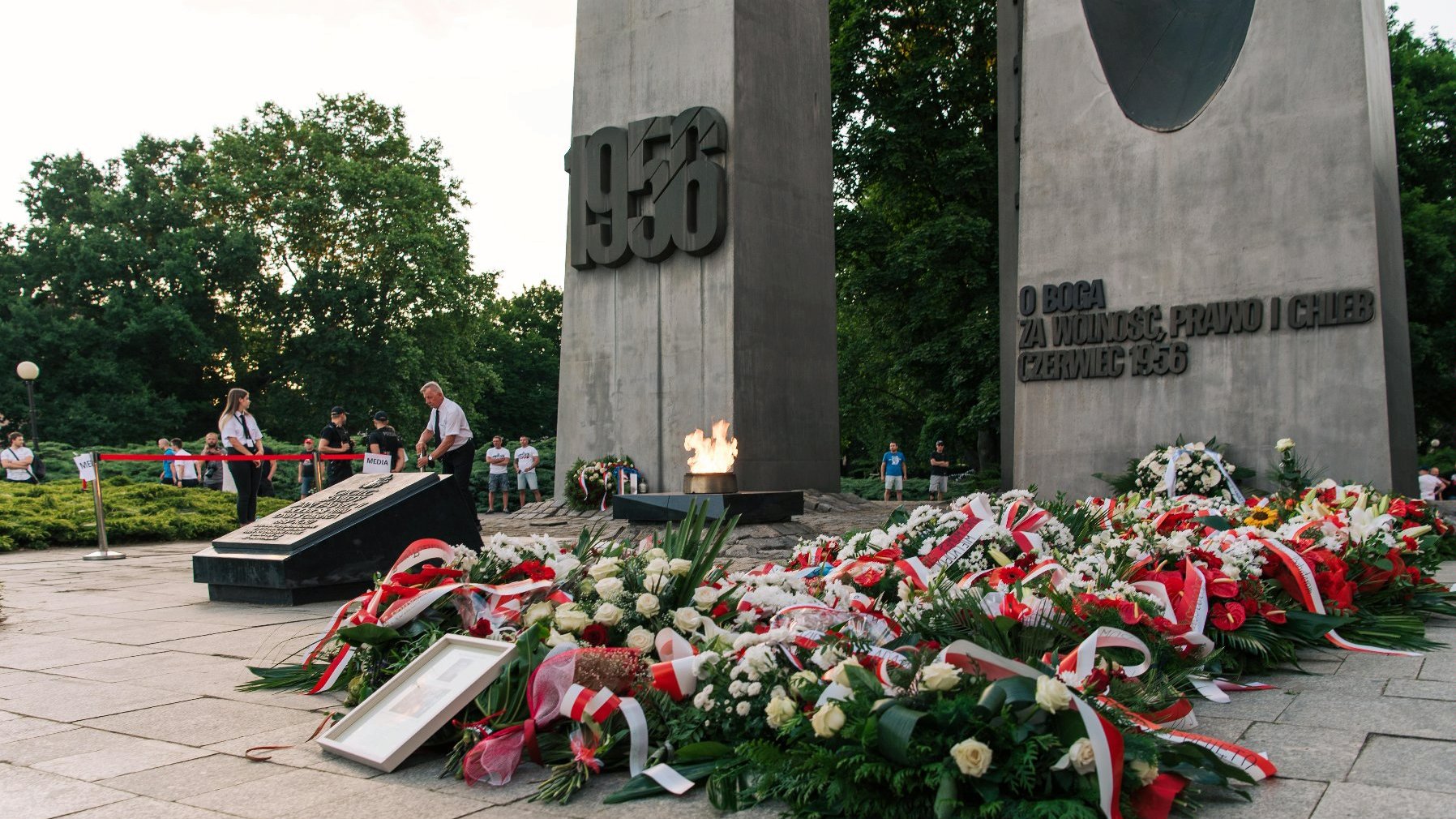 Zdjęcie przedstawia kwiaty przed pomnikiem dwóch krzyży. - grafika artykułu