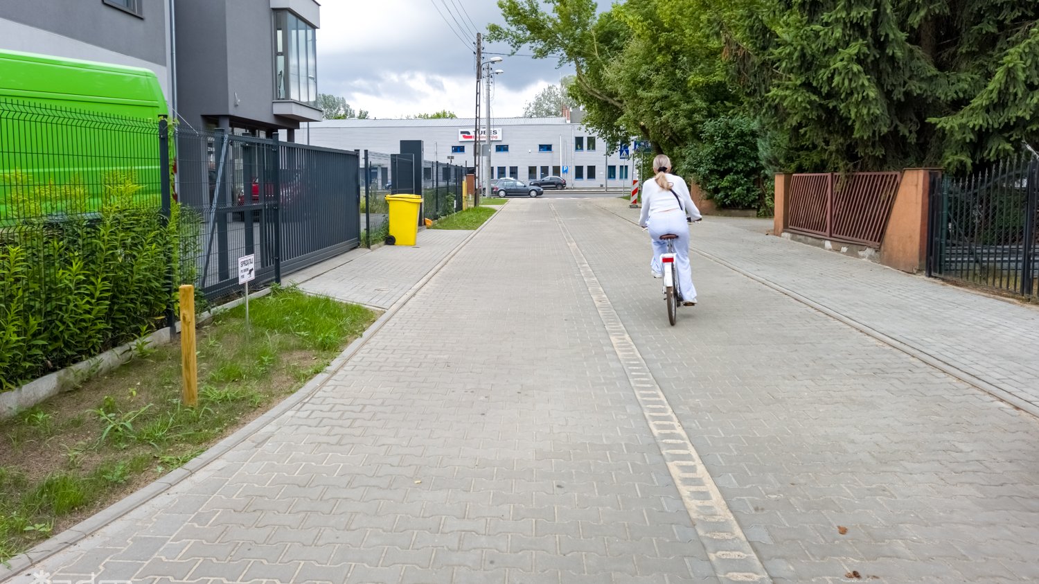 Zdjęcie przedstawia ulice, po której jedzie kobieta na rowerze.