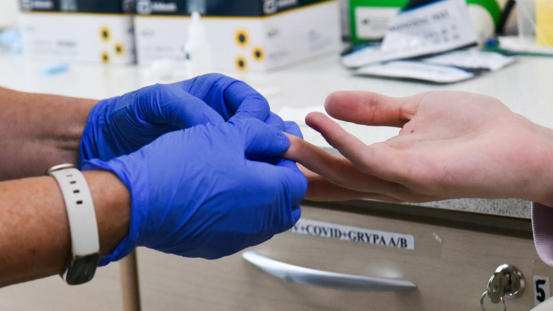 Na zdjęciu ręce w medycznych rękawiczkach pobierają komuś krew
