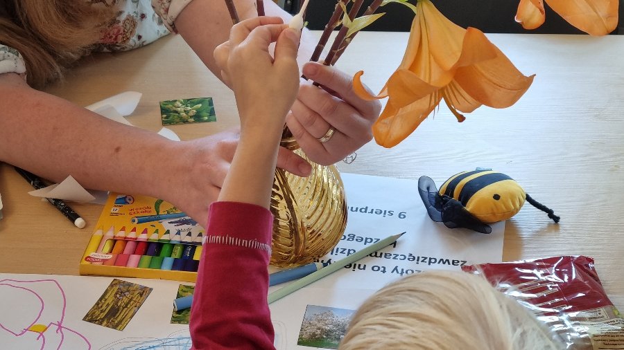Zdjęcie przedstawia dzieci tworzące prace plastyczne. Na fotografii widać tylko ich ręce.