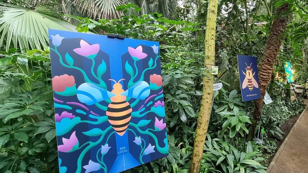 Zdjęcie przedstawia plakaty przedstawiające pszczoły stojące na tle roślin egzotycznych.