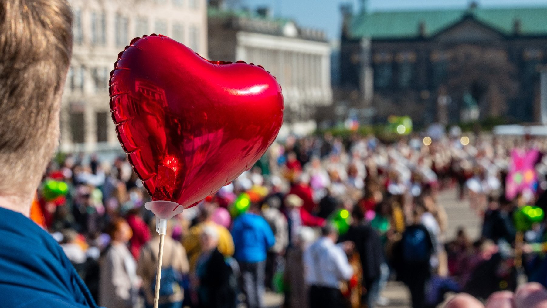 Na zdjęciu tłum ludzi na placu Wolności, na pierwszym planie człowiek z balonem w kształcie serca