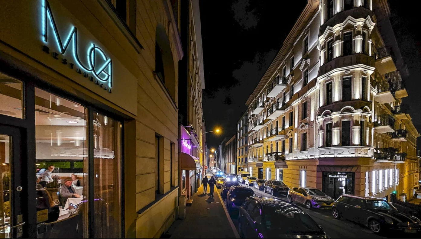 Na zdjęciu restauracja MUGA, obok inna kamienica, nocą - grafika artykułu