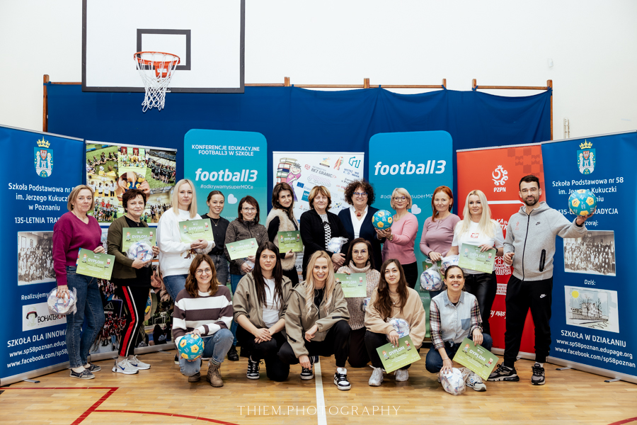 Konferencja edukacyjna "Football3 w szkole 2025" w Poznaniu, fot. Thiem.Photography - wspólne zdjęcie uczestniczek konferencji z dyplomami piłkami oraz innymi upominkami. W tle roll-upy reklamujące konferencję oraz kosz do gry w koszykówkę - grafika artykułu