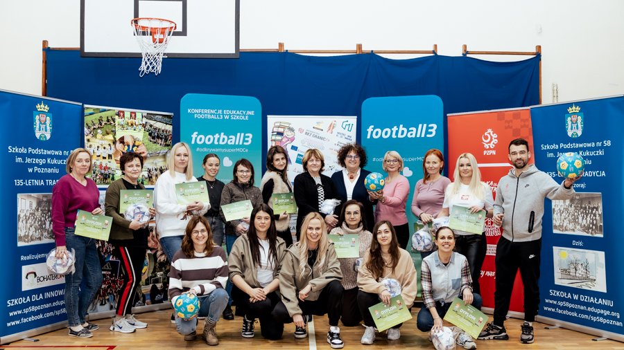 Konferencja edukacyjna "Football3 w szkole 2025" w Poznaniu, fot. Thiem.Photography - wspólne zdjęcie uczestniczek konferencji z dyplomami piłkami oraz innymi upominkami. W tle roll-upy reklamujące konferencję oraz kosz do gry w koszykówkę