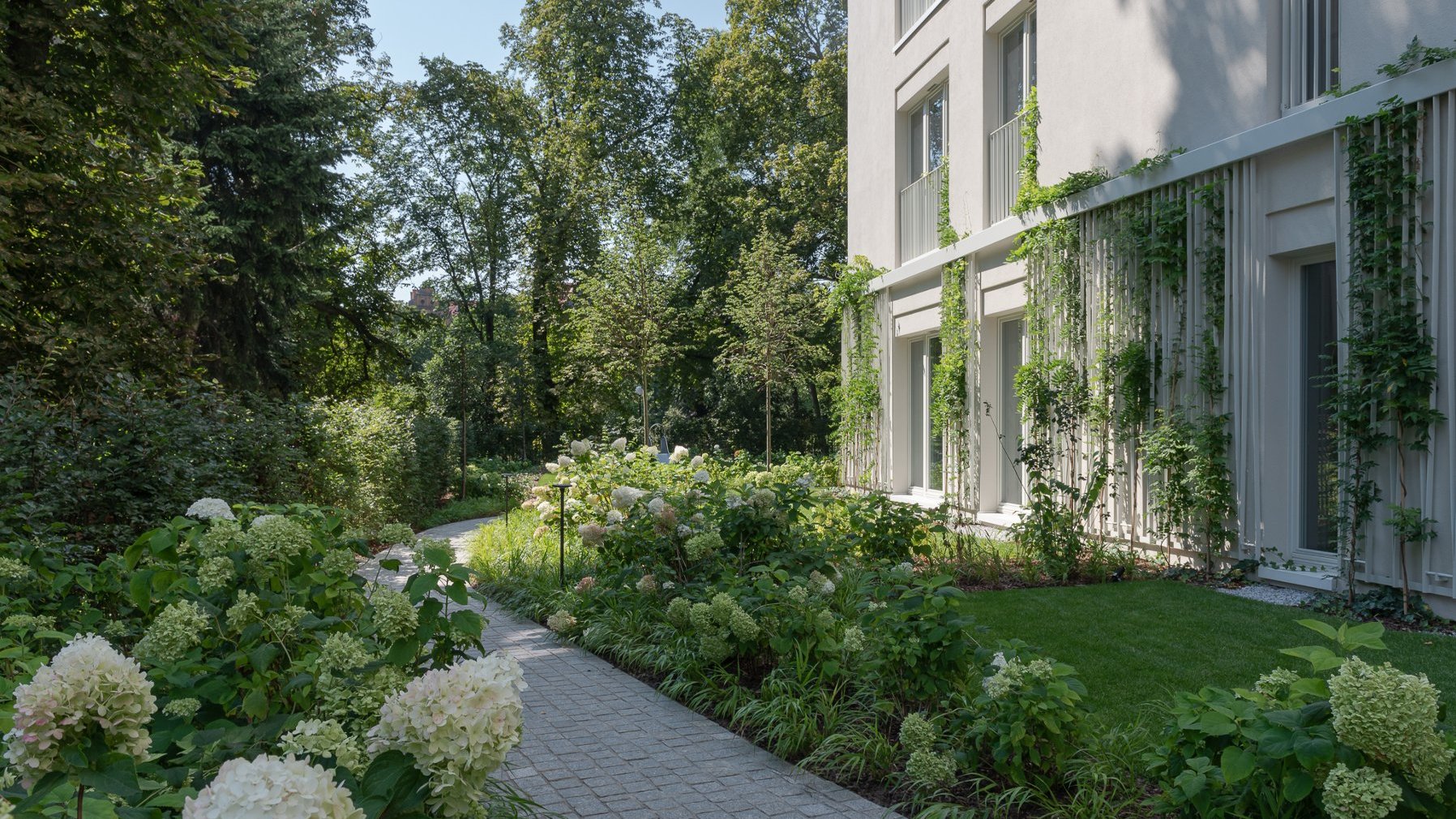 Gardens in front of Perfumiarnia. Lush greenery grows around the modern blocks of flats.