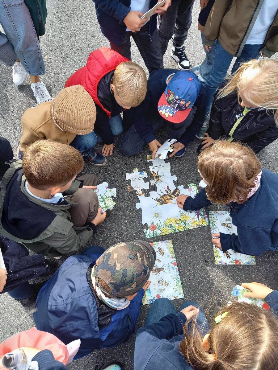 Zdjęcie przedstawia dzieci siedzace w okręgu i układające puzzle. - grafika artykułu