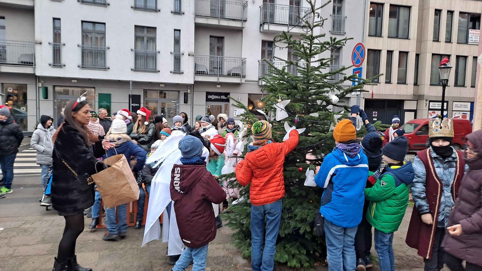 Zdjęcie przedstawia dzieci ubierające choinkę.