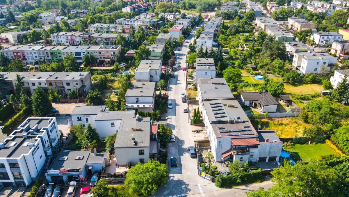 Zdjęcie przedstawia widok na budynki jednorodzinne, zieleń i drogi z lotu ptaka. - grafika artykułu