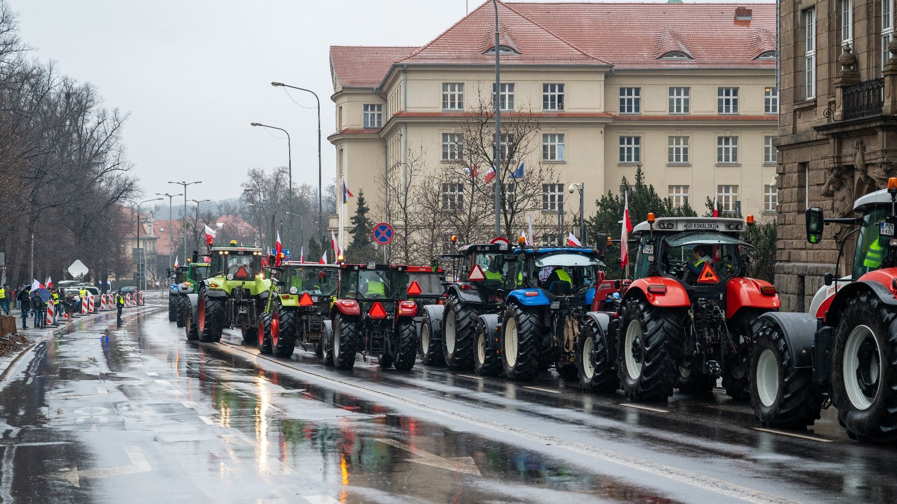 Zdjęcie przedstwia sznur ciągników na ulicy.