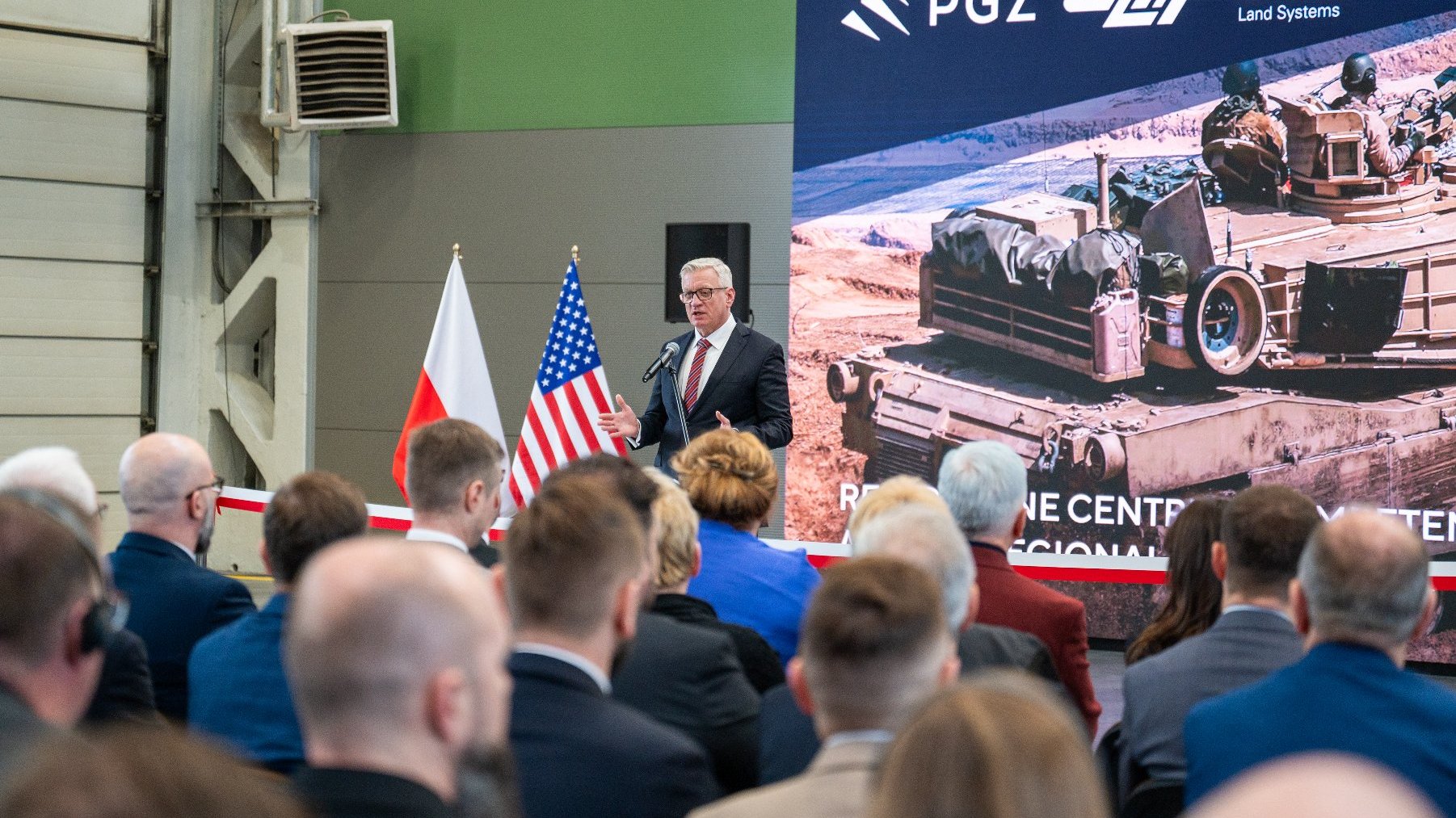 NA zdjęciu prezydent Poznania przy mikrofonie, w tle plakat czołgu, na pierwszym planie ludzie