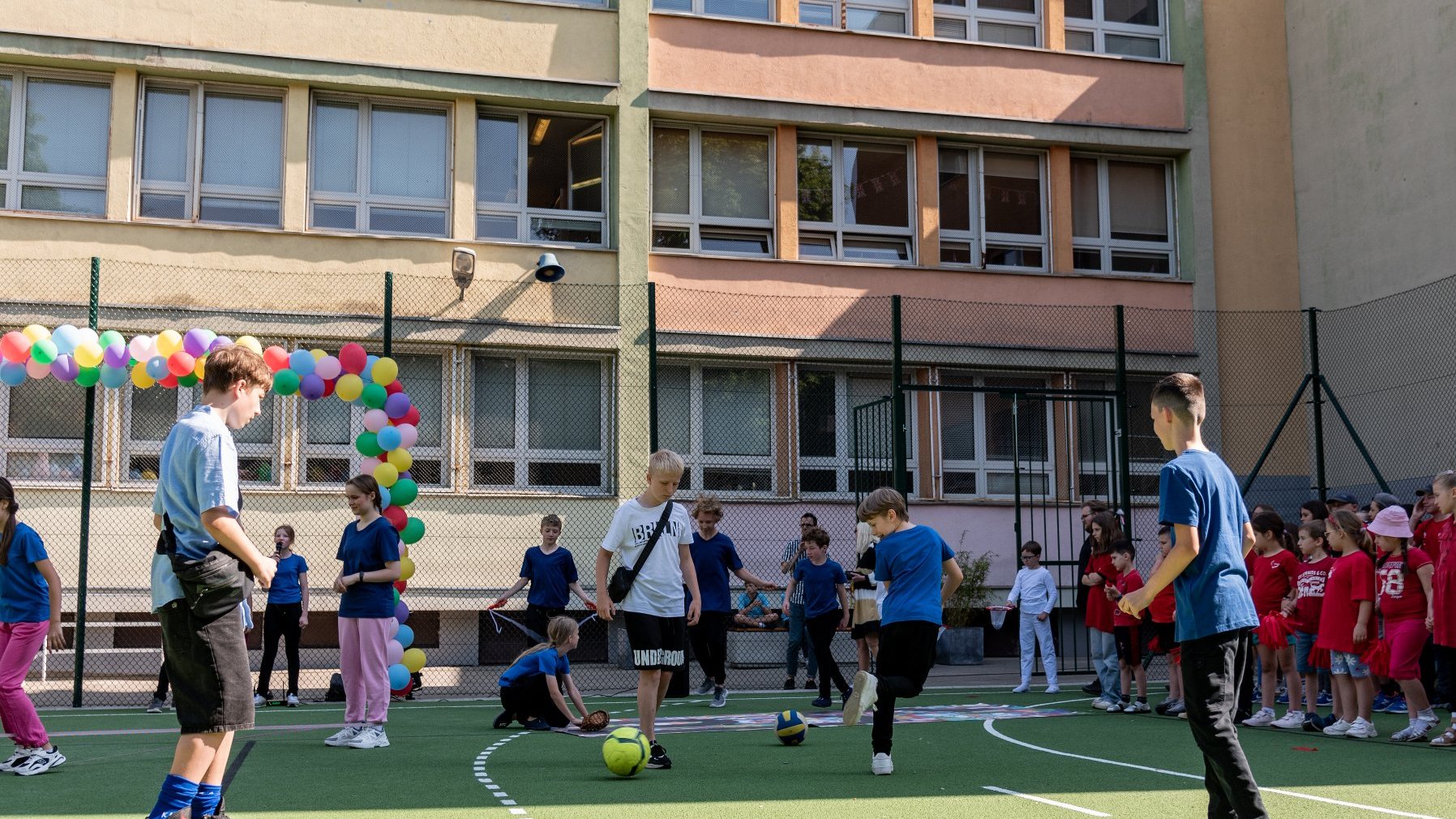 Zdjęcie przedstawia dzieci grające w piłkę na boisku.