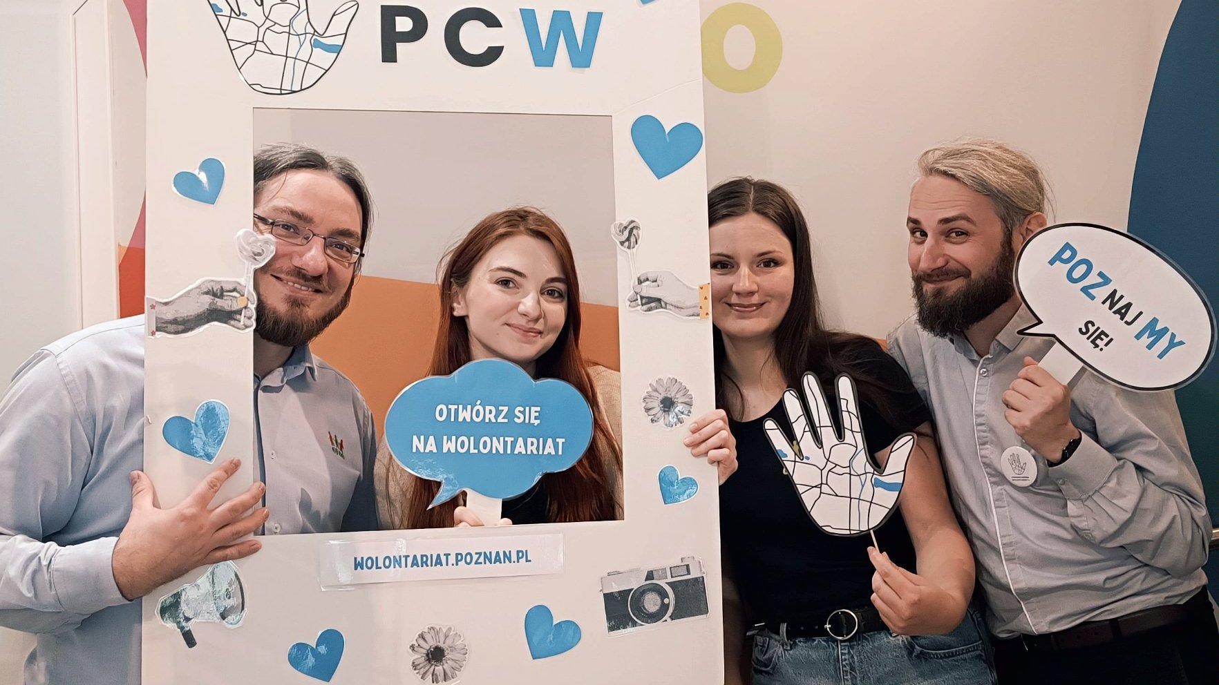 Grafika przedstawiająca cztery uśmiechnięte osoby: dwie kobiety i dwóch mężczyzn trzymających w ręku ramkę z napisem Poznańskie Centrum Wolontariatu, w tym jedna osoba trzyma hasło związane z wolontariatem.