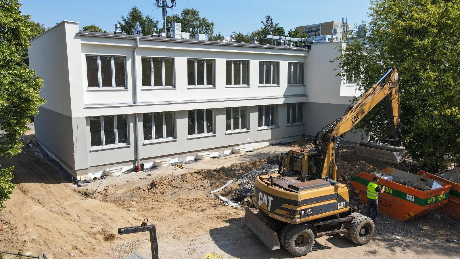 Zdjęcie przedstawia maszynę budowlana przed szkołą.