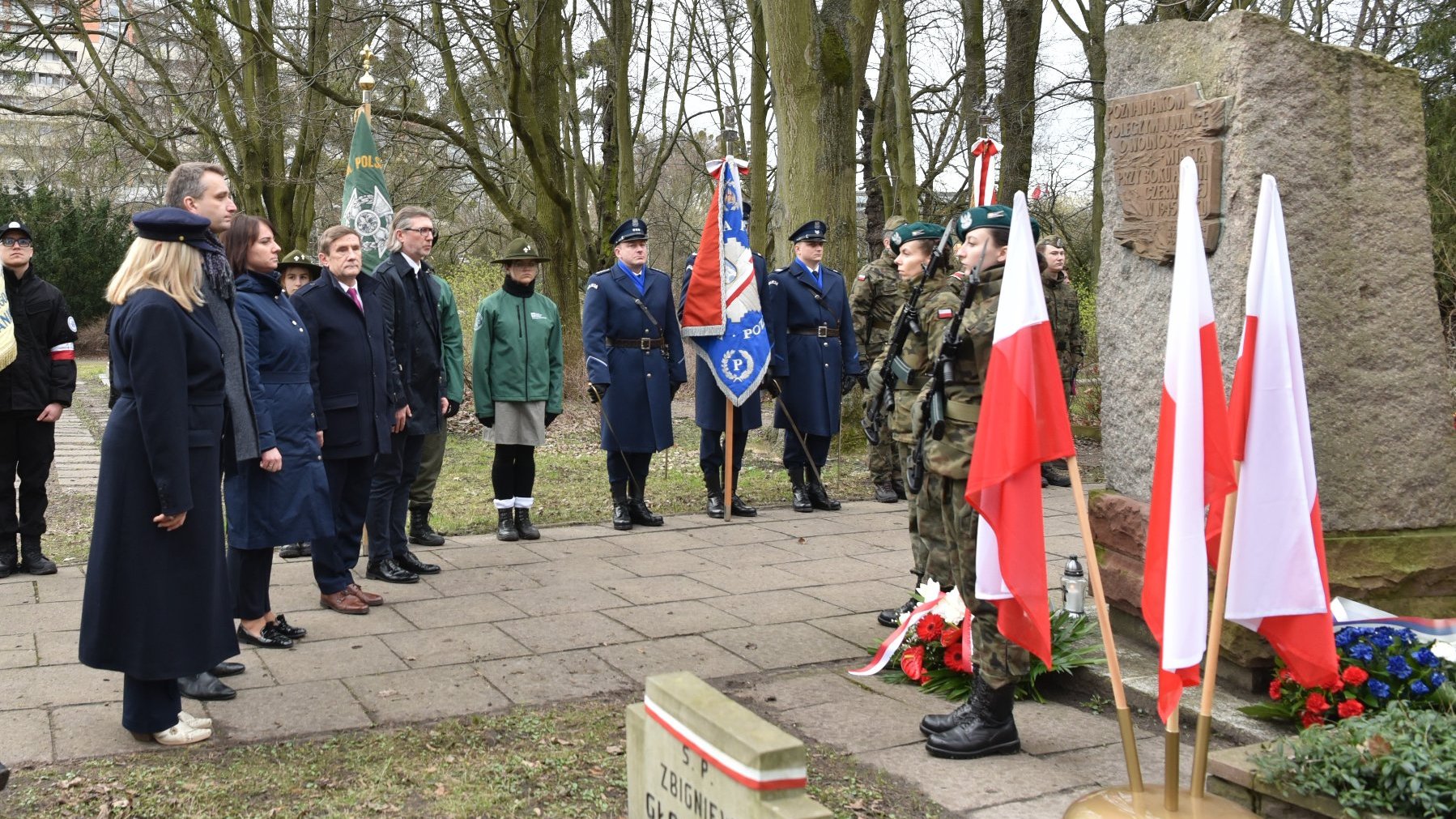 Zdjęcie przedstawia osoby skłądające kwiaty.