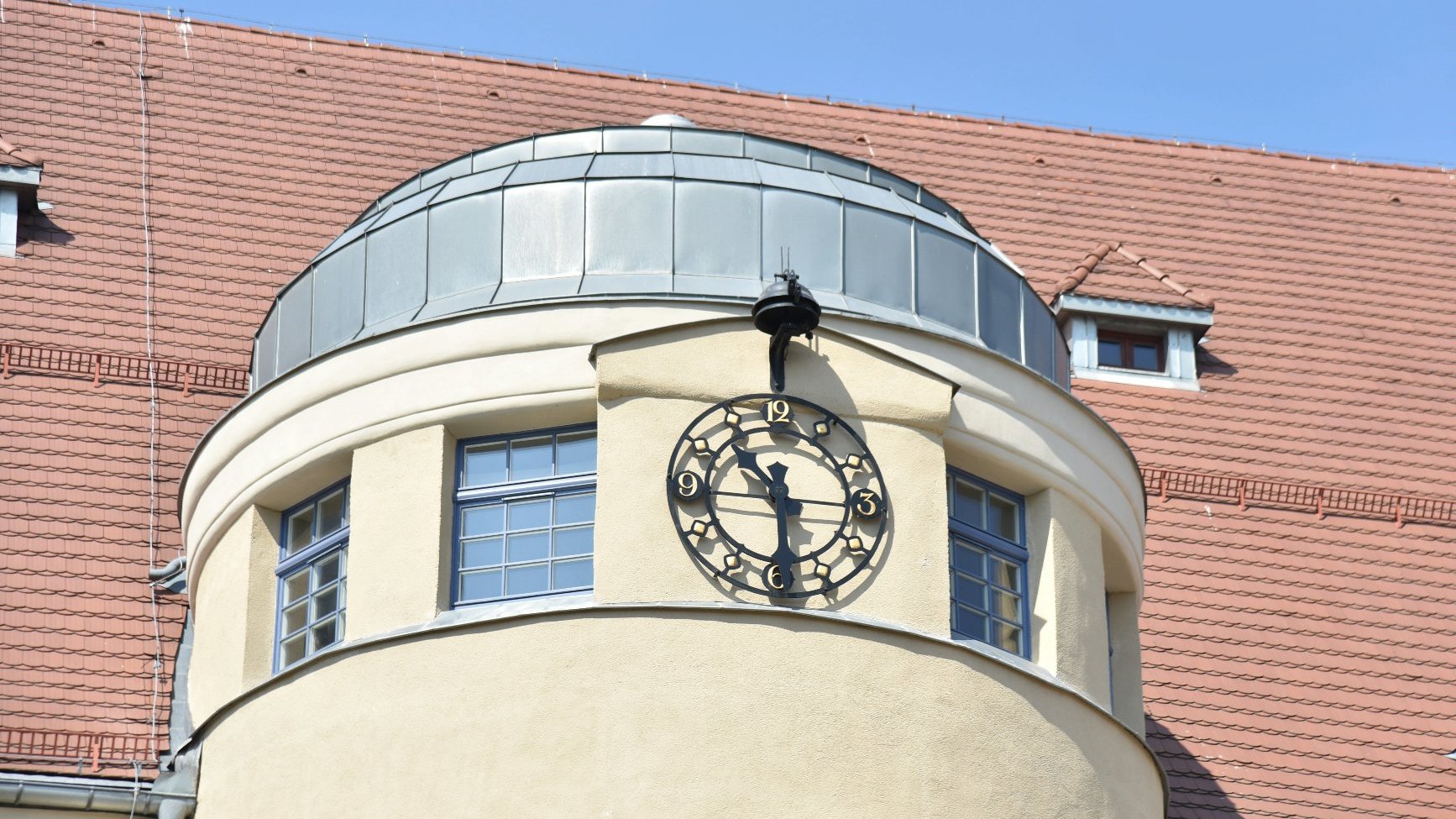 Zdjęcie przedstawia zegar na budynku szkoły.