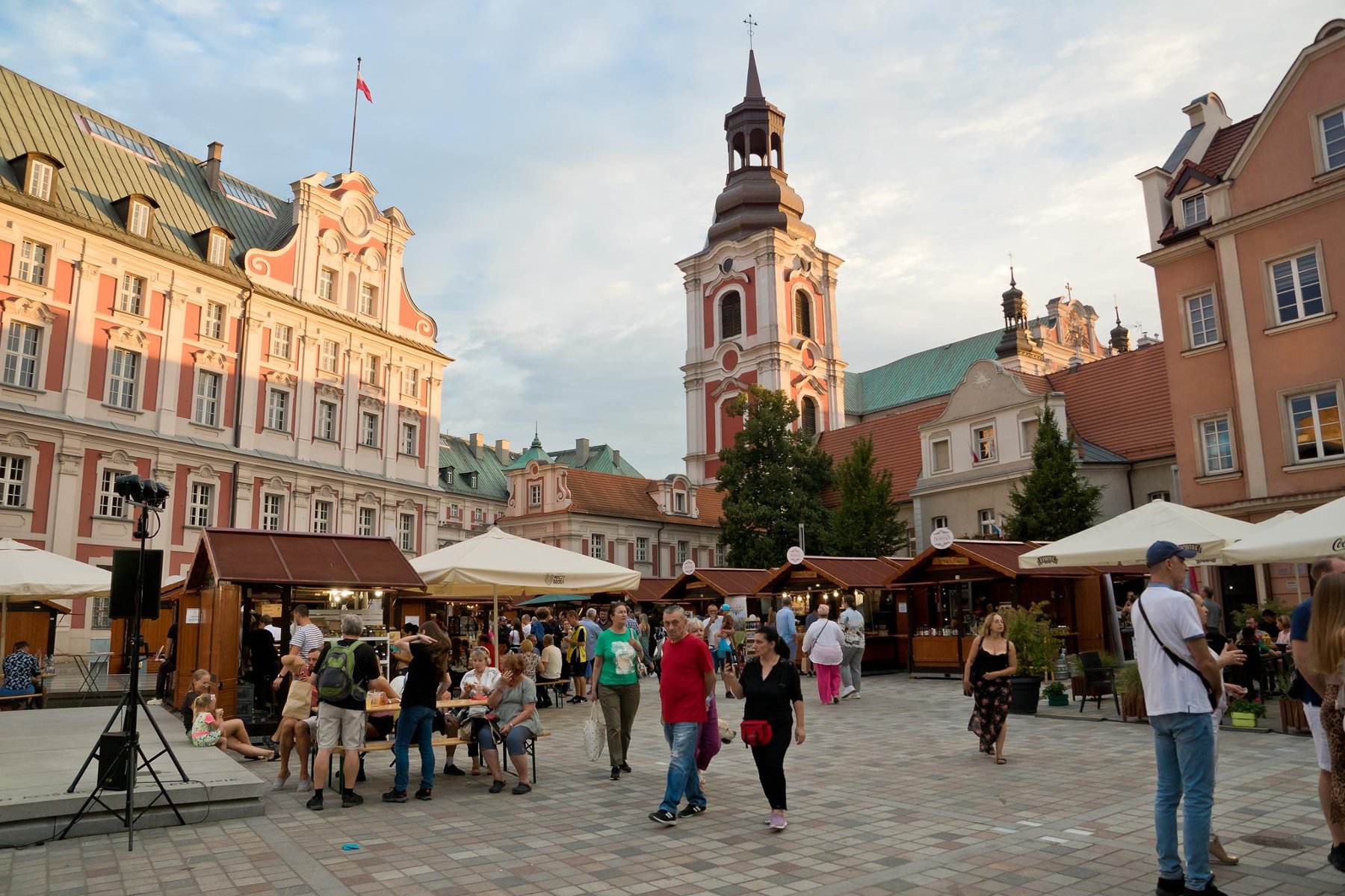 Zdjęcie przedstawia plac Kolegiacki, na kórym stoją stragany i spacerują ludzie. - grafika artykułu