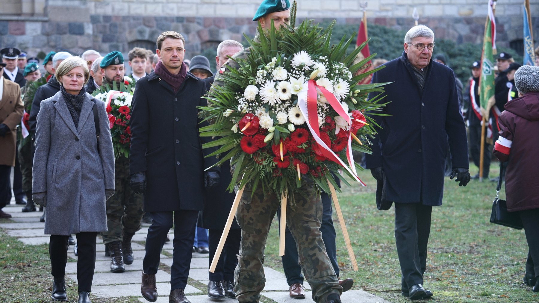 Na zdjeciu delegacja składająca kwiaty przed pomnikiem