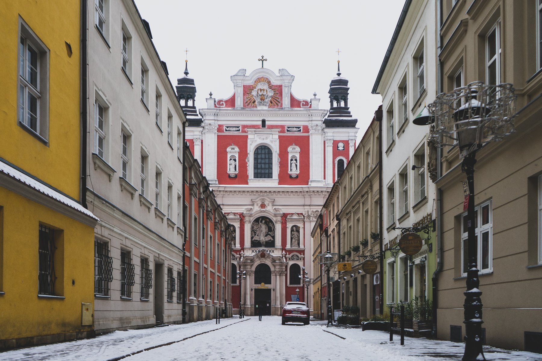 Na zdjęciu poznańska ulica, w tle fara, wszystko pokryte cieńką warstwą śniegu - grafika artykułu