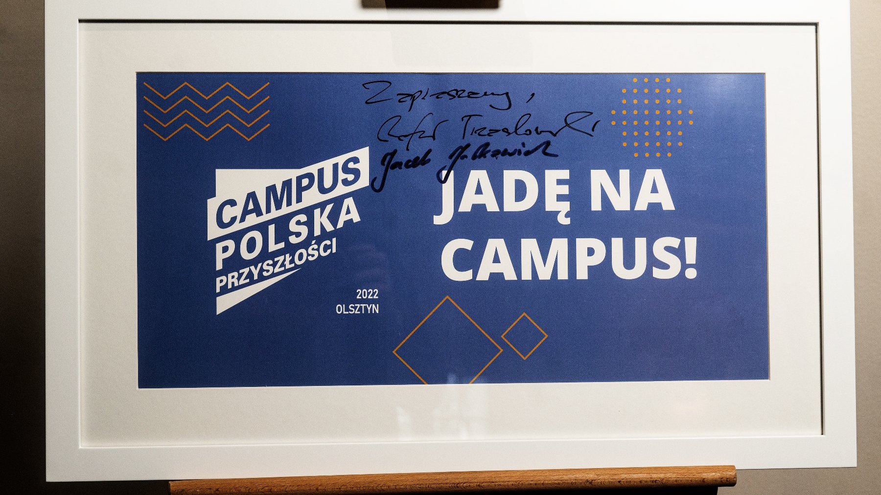 Oprawiona grafika zaproszenia na zeszłoroczny "Campus Polska Przyszłości" z autografami Jacka Jaśkowiaka, prezydenta Poznania oraz Rafała Trzaskowskiego, prezydenta Warszawy.