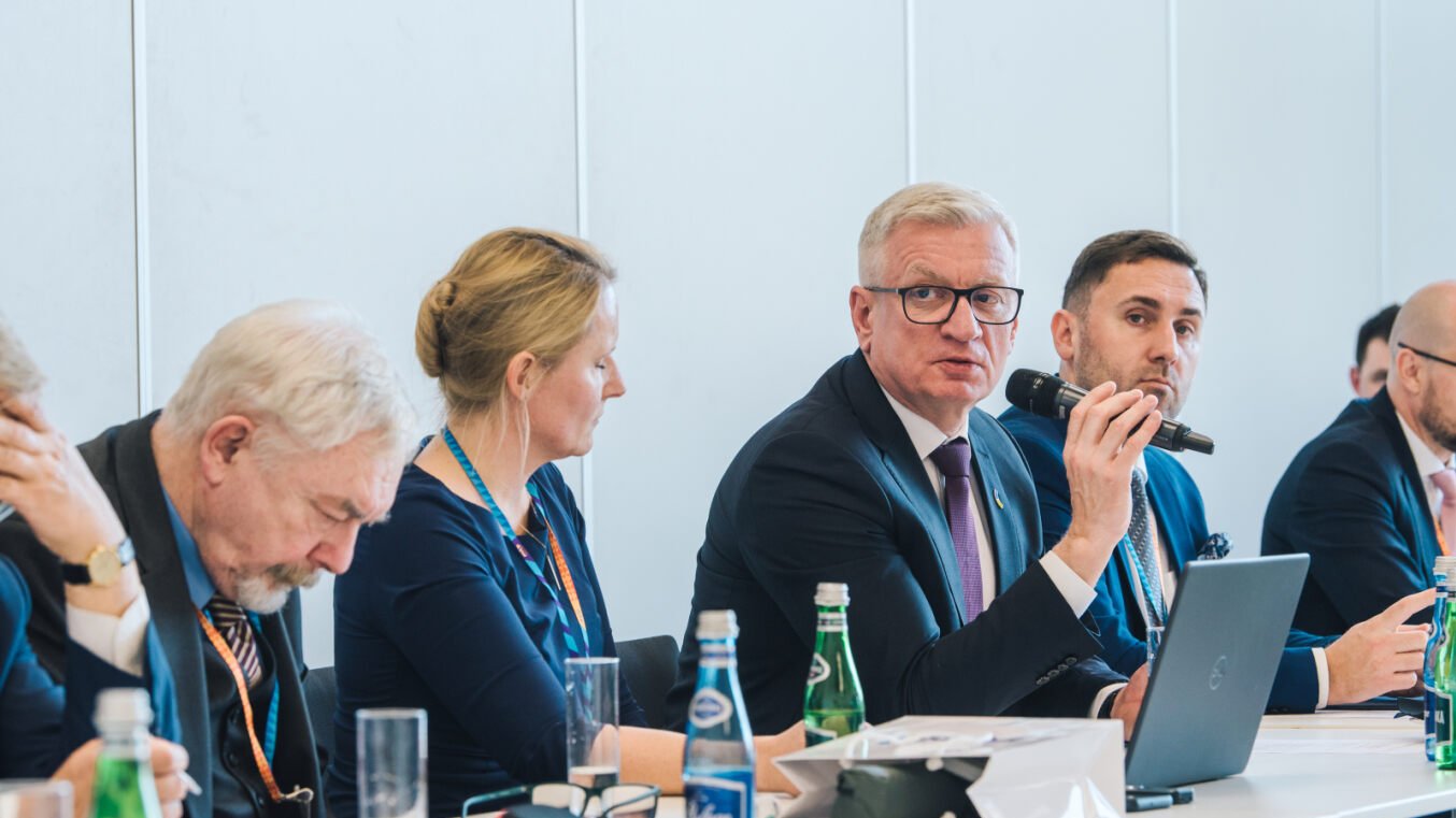 Na zdjęciu ludzie przy stole konferencyjnym, wśród nich prezydent Poznania z mikrofonem w ręku