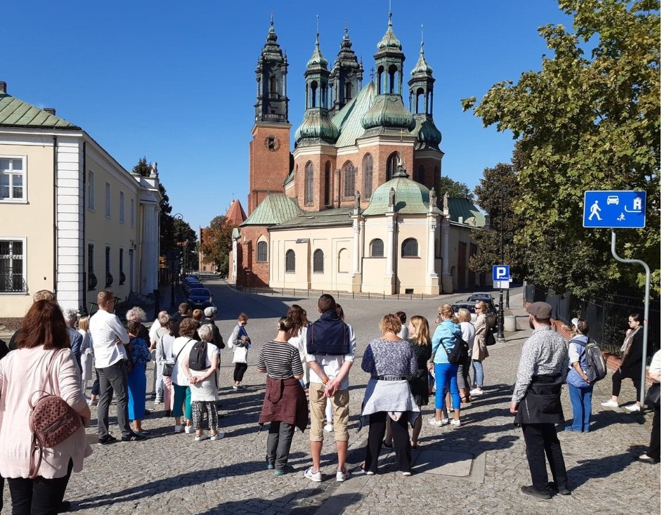 Grupa uczestników przechadzki przed kościołem, będącym jednym z punktów zwiedzania. - grafika artykułu