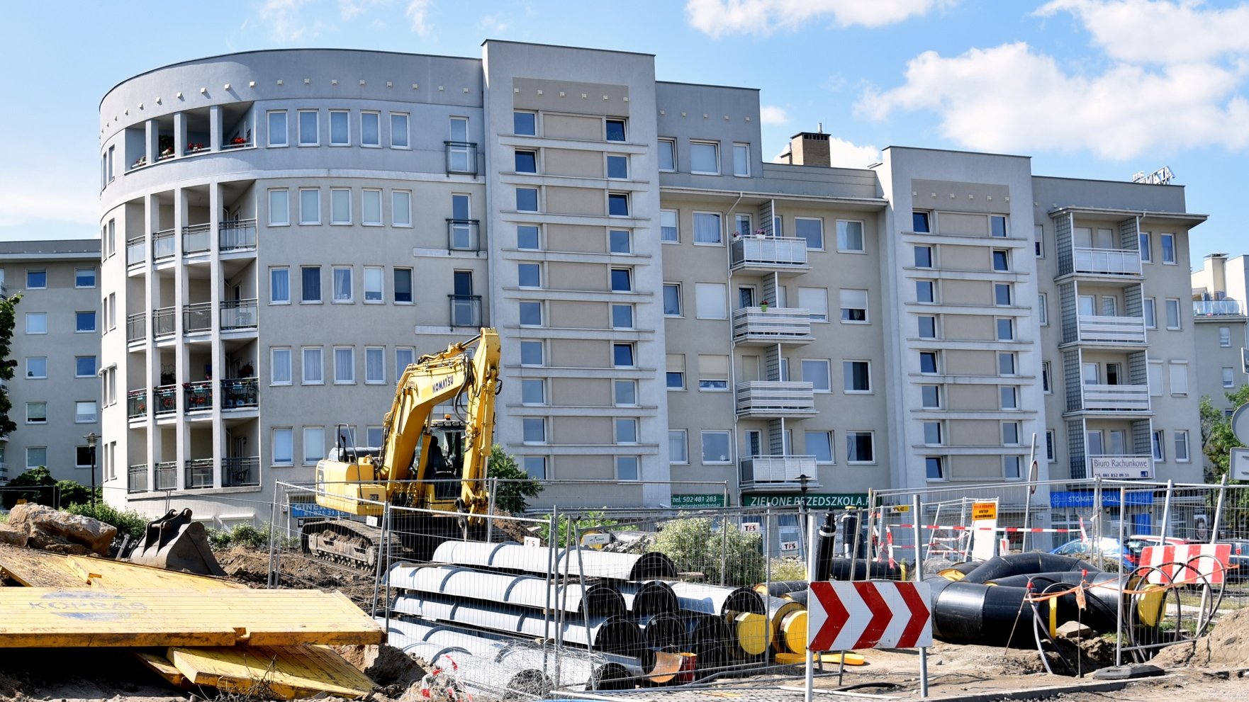 Na zdjęciu widać maszyny i elementy budowlane na tle bloku