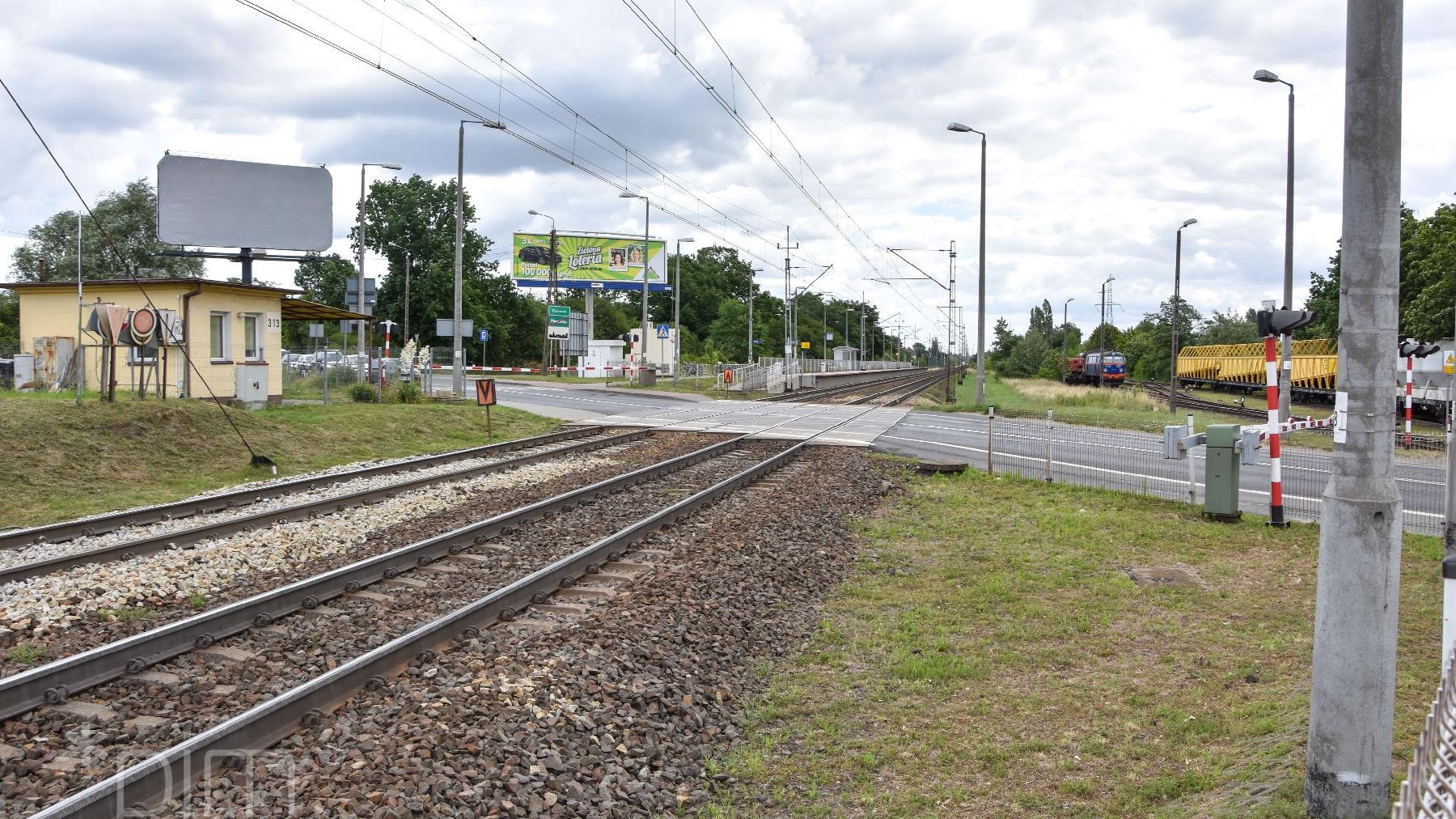 Widok na przejazd kolejowy i zamknięte szlabany.