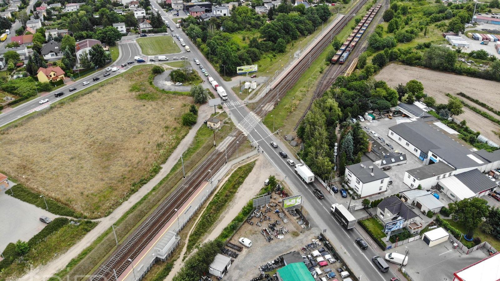 Widok z góry na stojące 2 sznury samochodów przed zamkniętymi szlabanami.