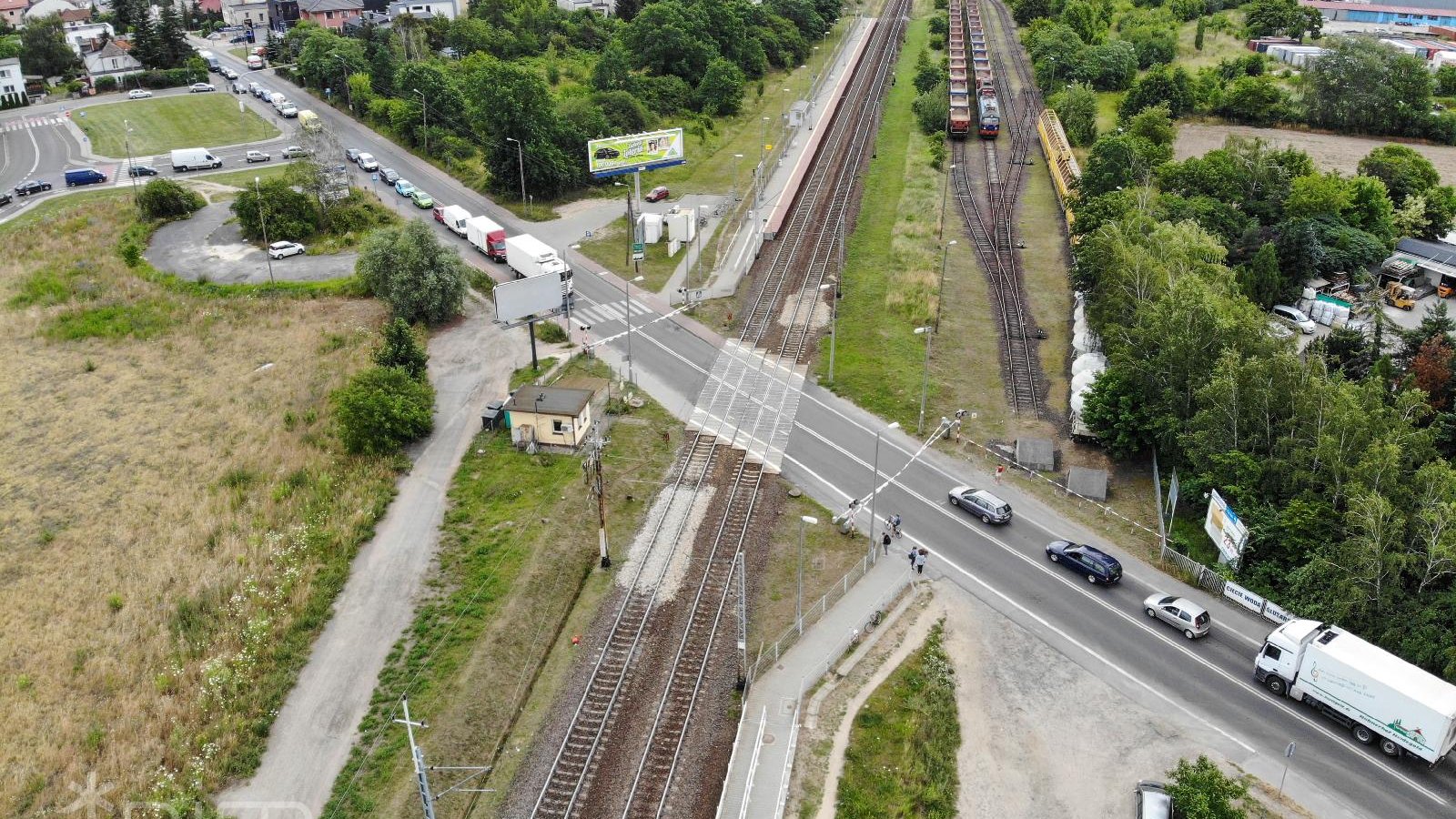 Widok z góry na drogę przecinającą tory kolejowe.