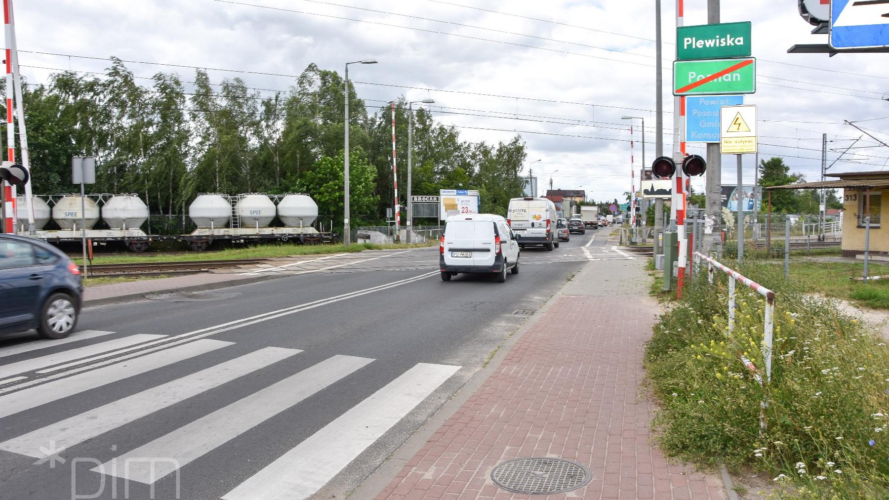 Samochody przejeżdżają przez przejazd kolejowy.