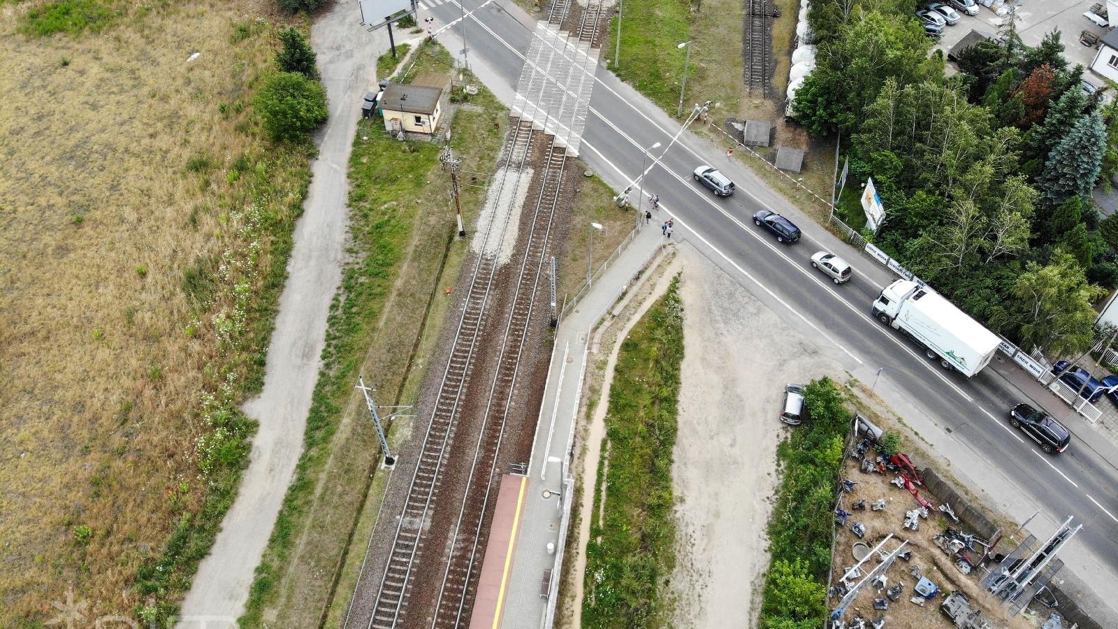 Widok z góry na zamknięty przejazd kolejowy i stojące przed szlabanem samochody.