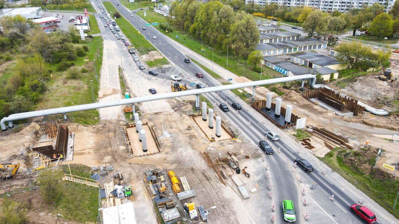 Widok z góry na budowę wiaduktu. Rury ciepłownicze nad czynna drogą oraz podpory wiaduktu.