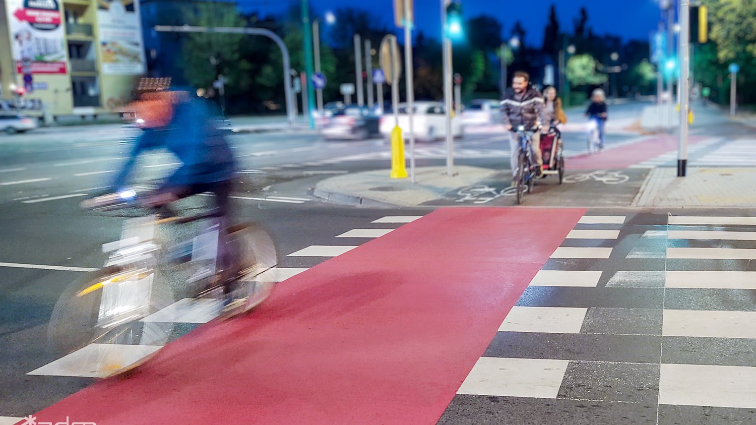 Zdjęcie skrzyżowania ulic z jadącymi rowerzystami.
