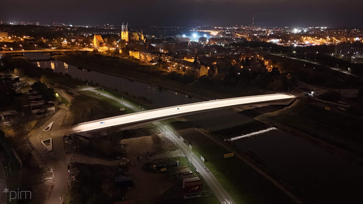 Zdjęcie z lotu ptaka na Poznań nocą i intensywnie oświetlone mosty Berdychowskie.