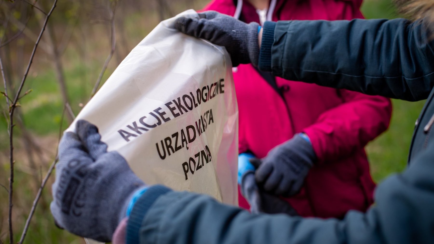 Zdjęcie przedstawia osobę trzymającą w rękach worek z napisem "Akcje ekologiczne Urząd Miasta Poznania".