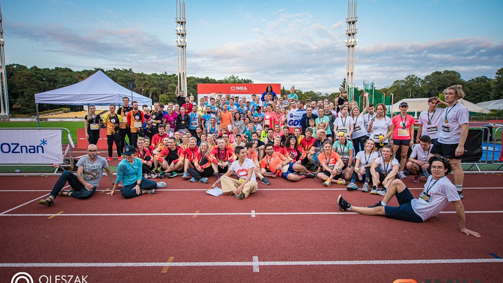 Zdjęcie przedstawia grupę ludzi pozujących do wspólnego zdjęcia na bieżni.