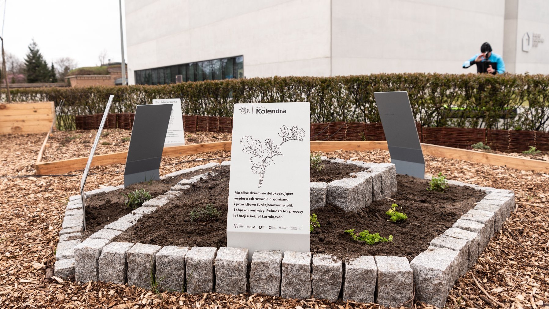 Galeria zdjęć przedstawia ogród eksperymentalny. Widać na nim wydzielone miejsce na rośliny oraz prelegentów konferencji.