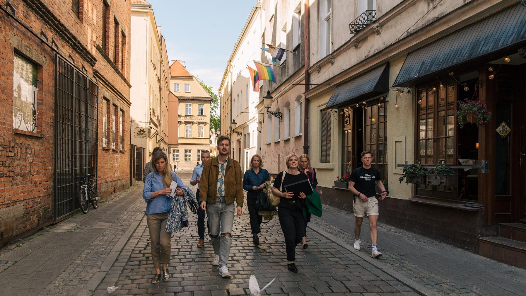 Na zdjęciu grupa ludzi idzie uliczką Starego Miasta w Poznaniu