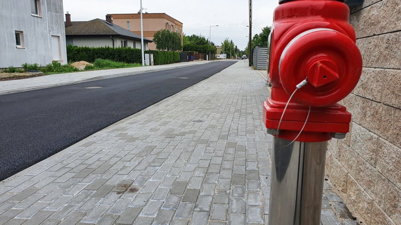 Na zdjęciu ulica z nowo położonym chodnikiem i nową nawierzchnią, na pierwszym planie czerwony hydrant