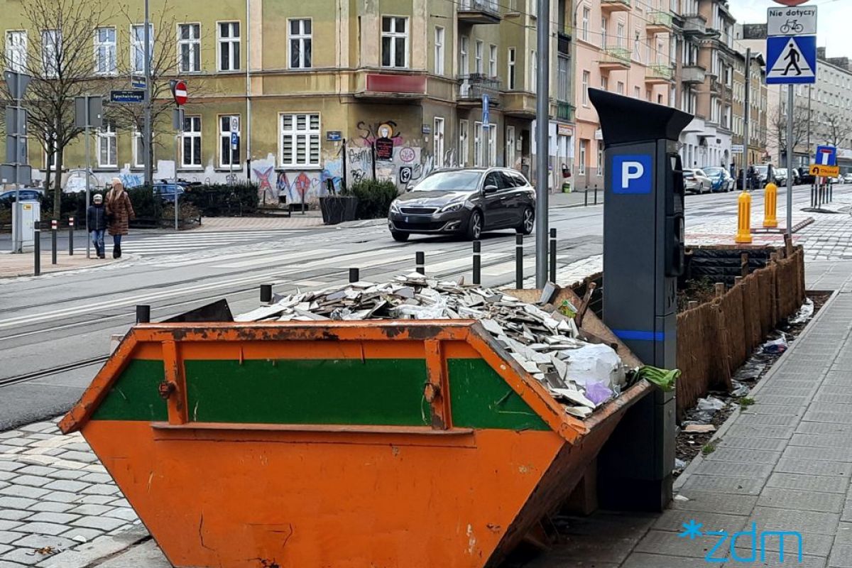 Zdjęcie przedstawia kontener na śmieci ustawiony na chodniku - grafika artykułu