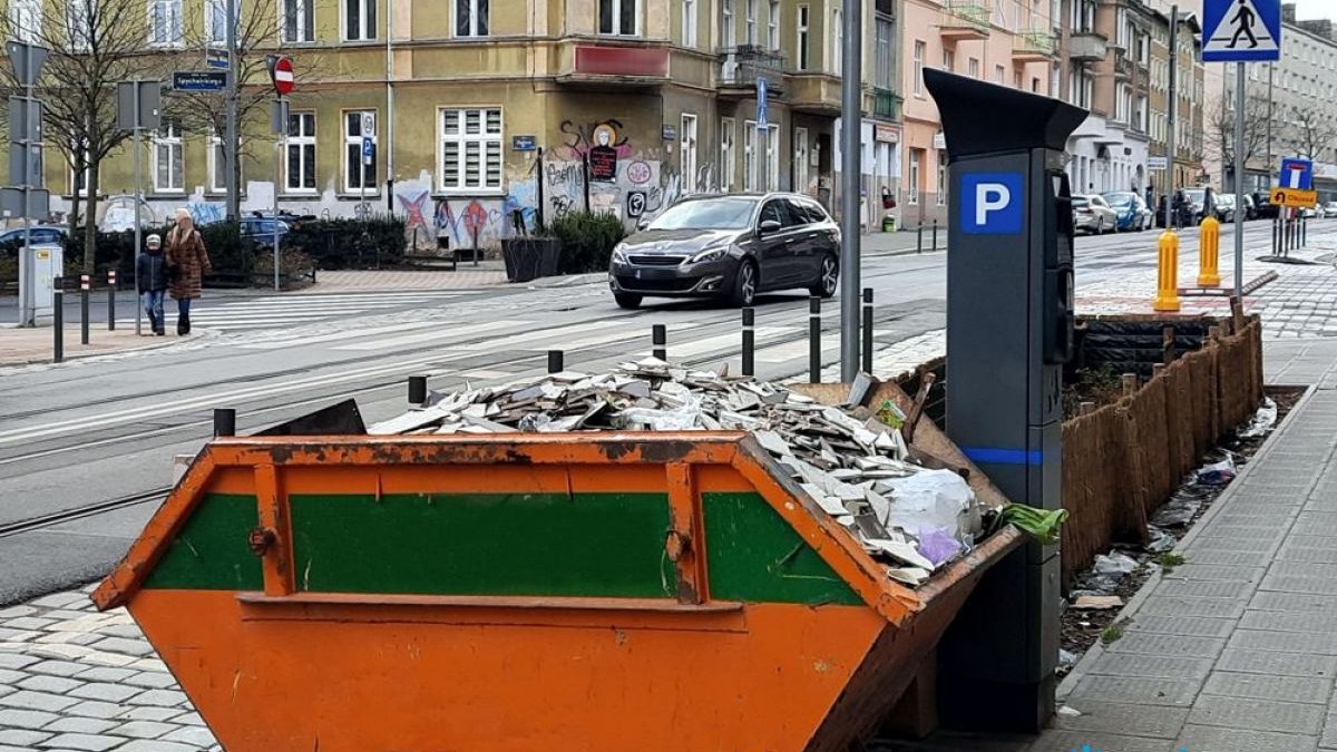 Zdjęcie przedstawia kontener na śmieci ustawiony na chodniku