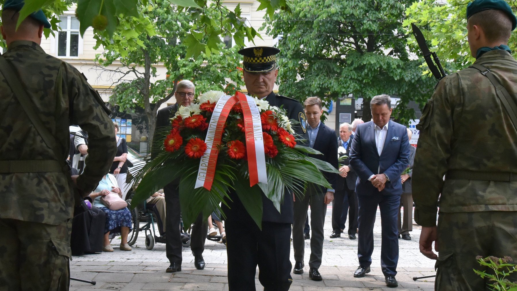 Na zdjęciu przedstawiciele władz Miasta i regionu składają kwiaty, na pierwszym planie strażnik miejski z wieńcem