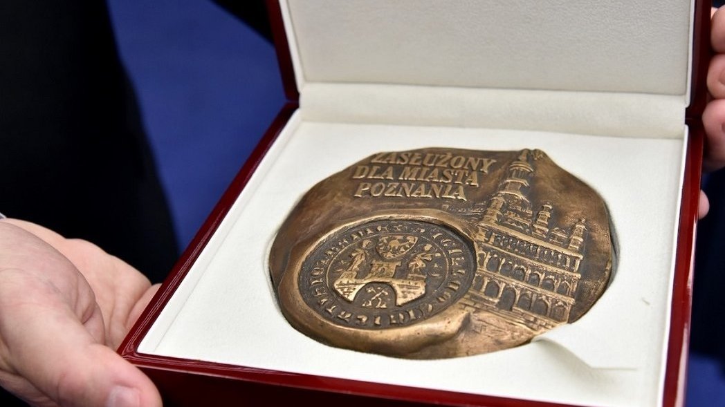 Na zdjęciu medal "Zasłużony dla Miasta Poznania" w pudełku, trzymany w dłoniach - grafika artykułu